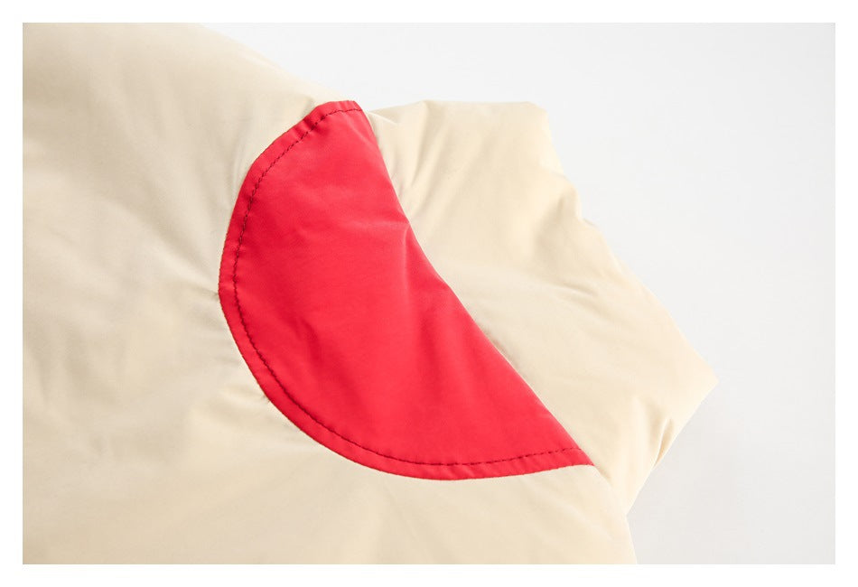 Close-up of a curved red inset panel stitched onto a cream garment.