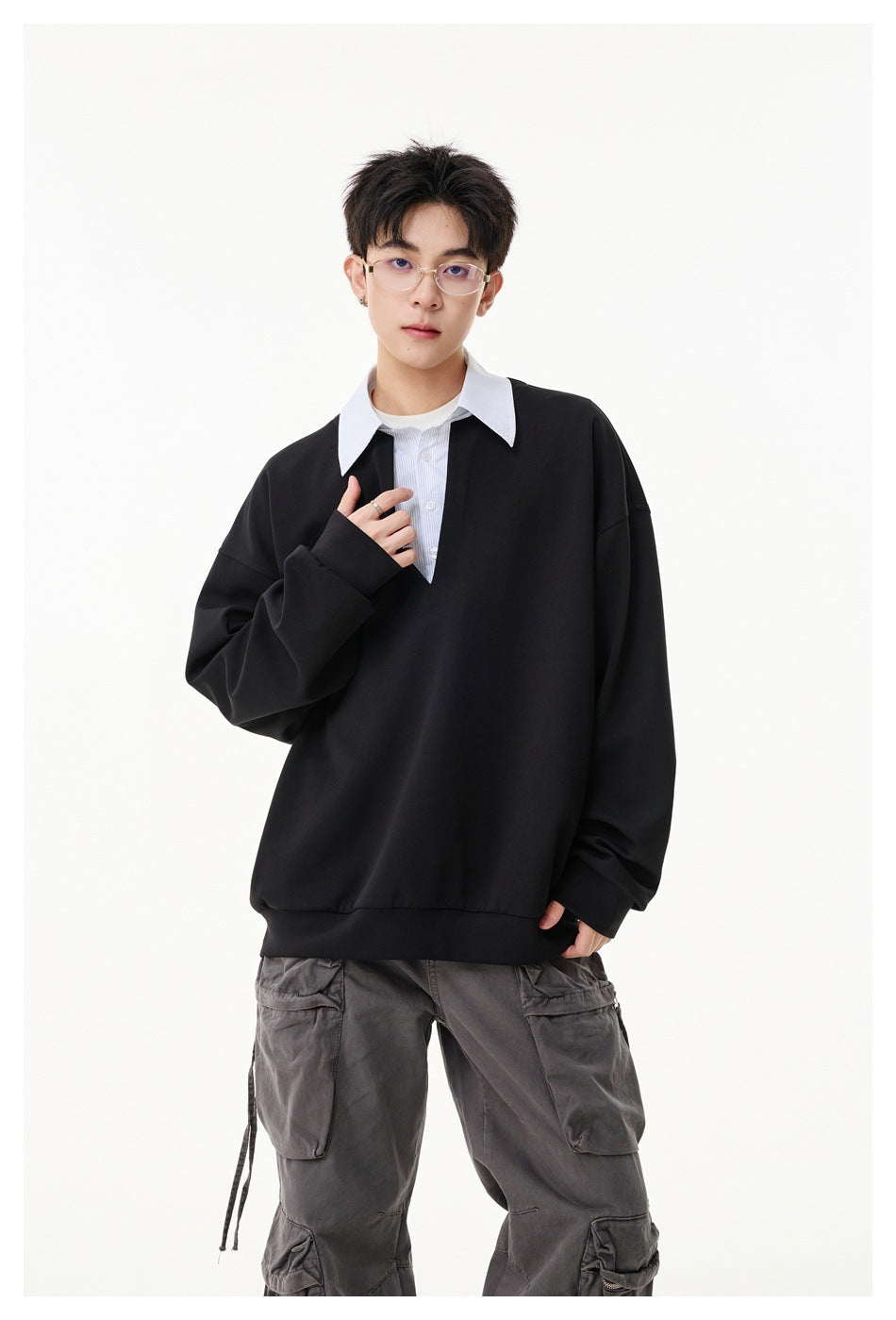Front view of a model wearing a black oversized pullover with a white striped collar and button placket.