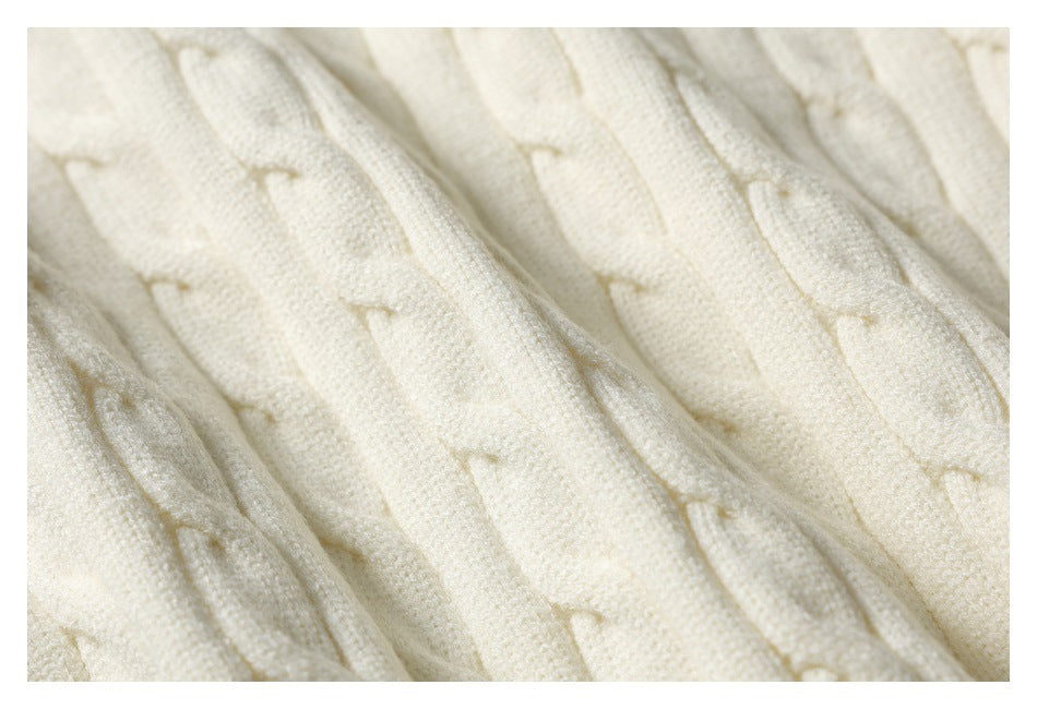 Macro view of ivory knit fabric with raised cable-like stitches and textured loops.