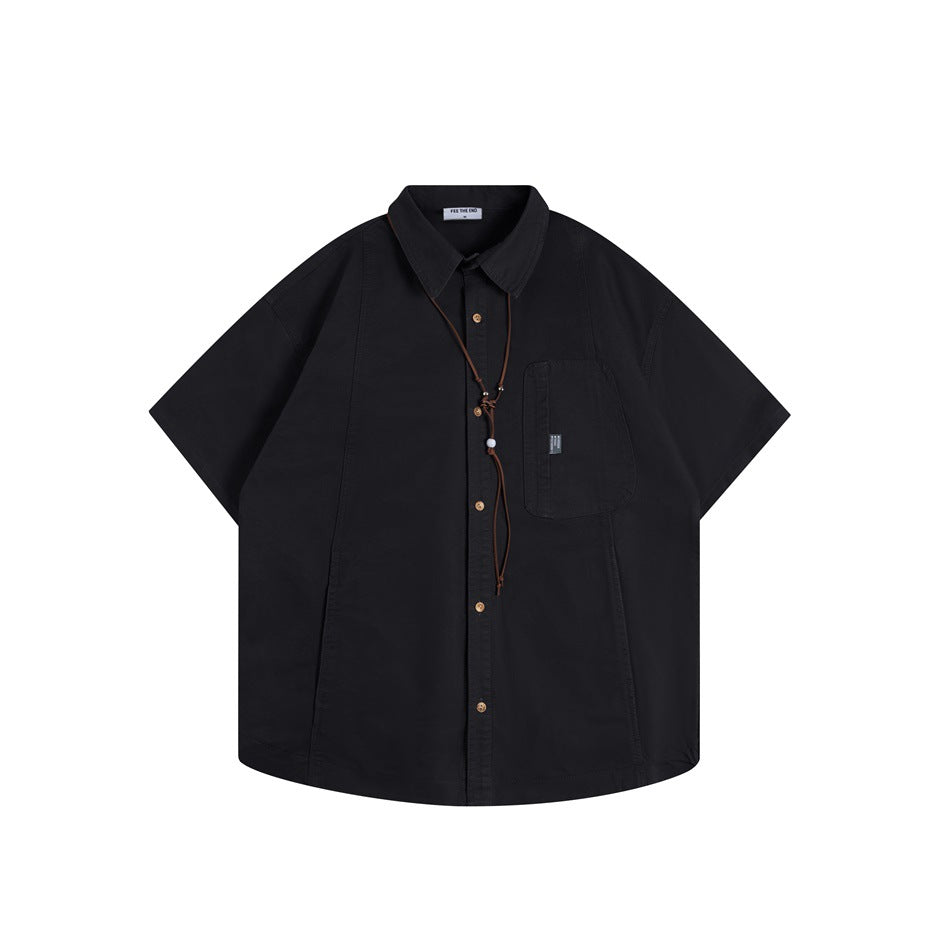 Black short-sleeve button-up shirt, front flat lay, with chest pocket and brown cord necklace