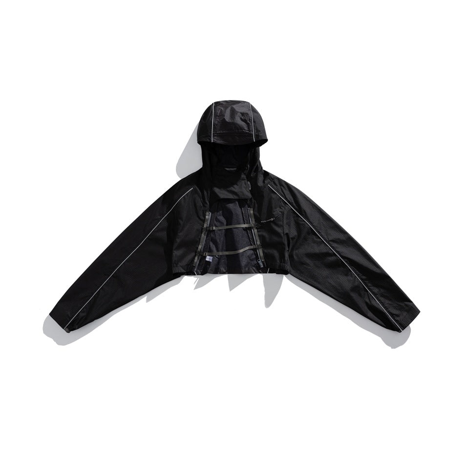 Black hooded cropped jacket with wide sleeves, reflective piping and horizontal chest straps, shown from the front.