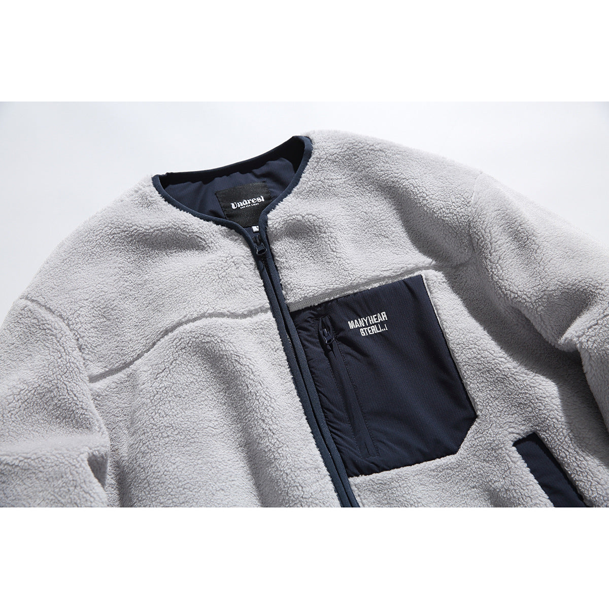 Close-up of a light gray fleece zip jacket with navy trim and a large navy chest pocket.