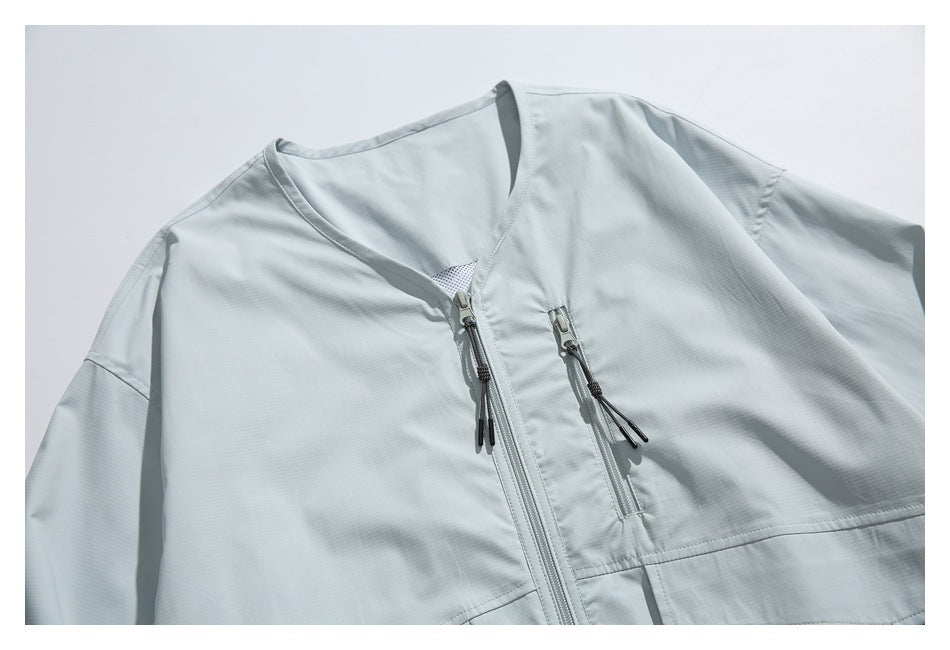Close-up of a pale gray jacket's upper front with a stand collar, central zipper, and vertical zip pocket.