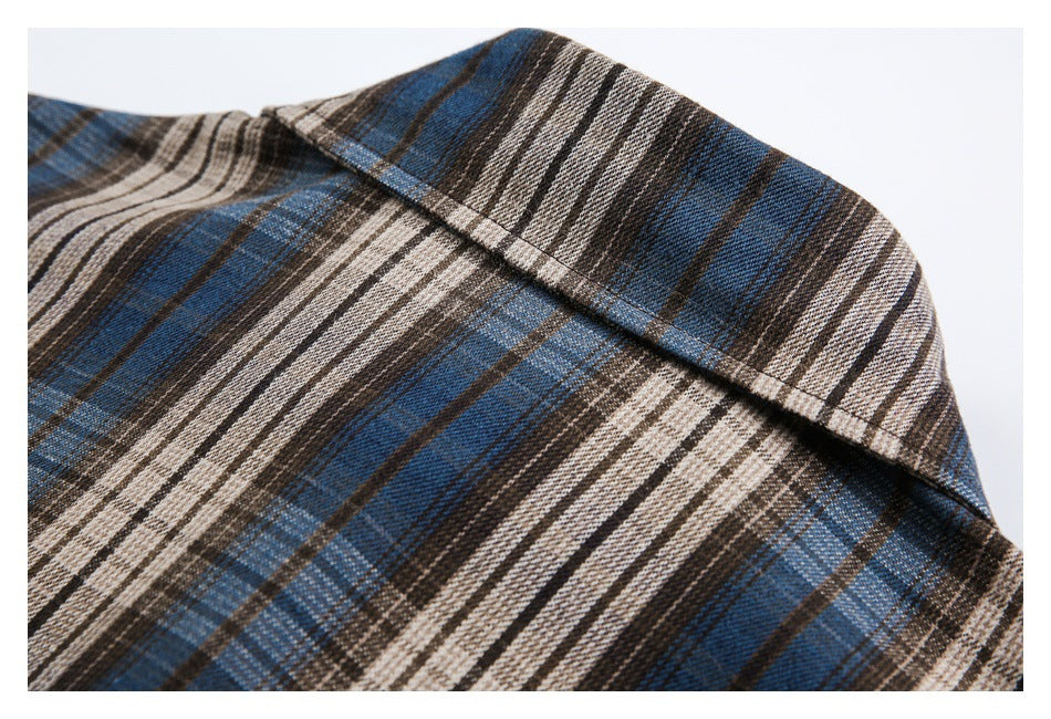 Close-up of the pointed collar on a blue, brown, and cream plaid shirt.