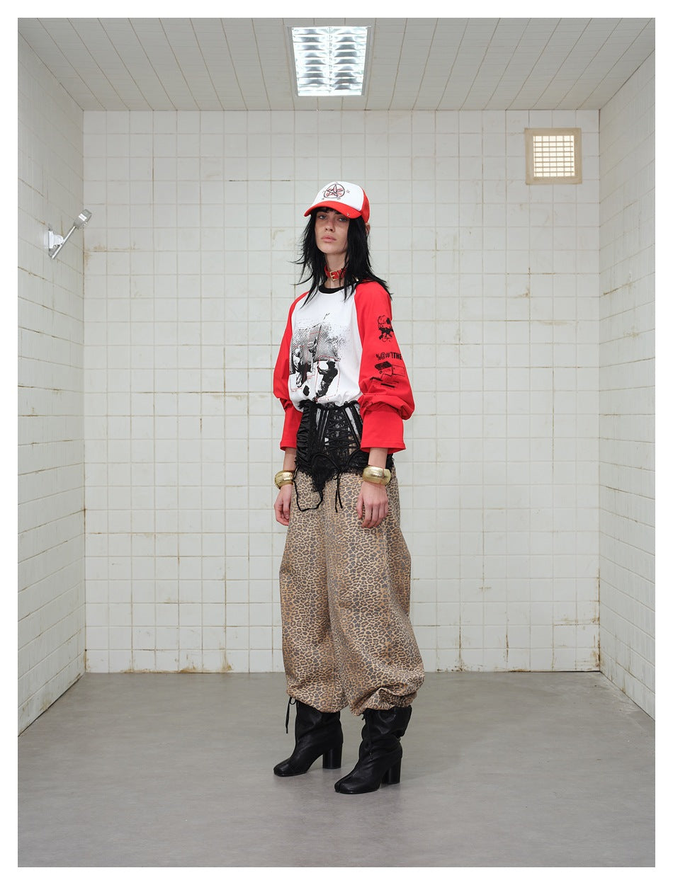 Model wearing a white graphic raglan shirt with red sleeves, a black corset, leopard-print trousers and black boots.