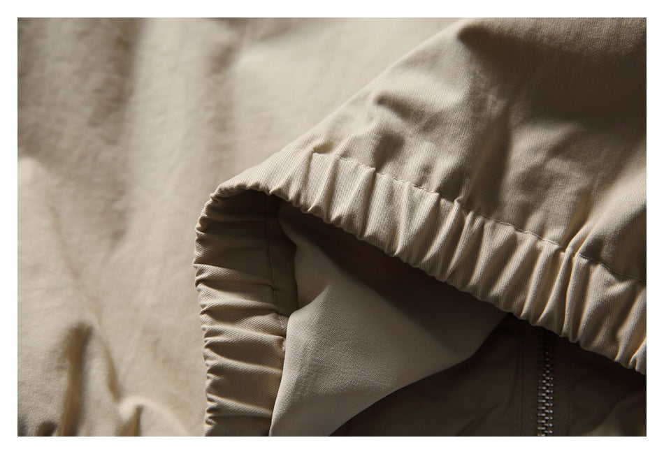 Close-up of a beige garment with a gathered elastic edge and a visible zipper.