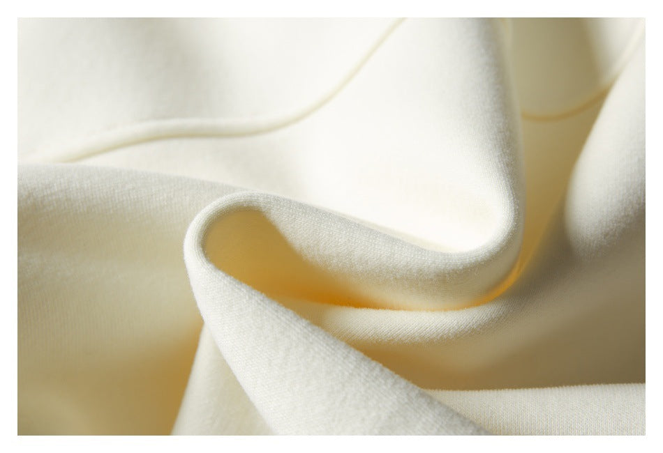 Close-up of ivory fabric draped into folds, showing its smooth surface and finished edge.