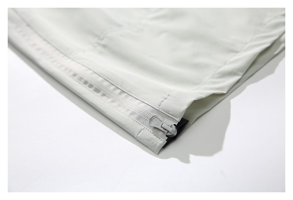 Close-up of a pale gray pant leg hem with a short zipper and visible stitching.
