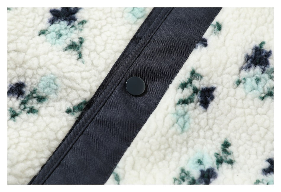 Close-up of a dark snap button and placket on the jacket's cream floral sherpa fabric.
