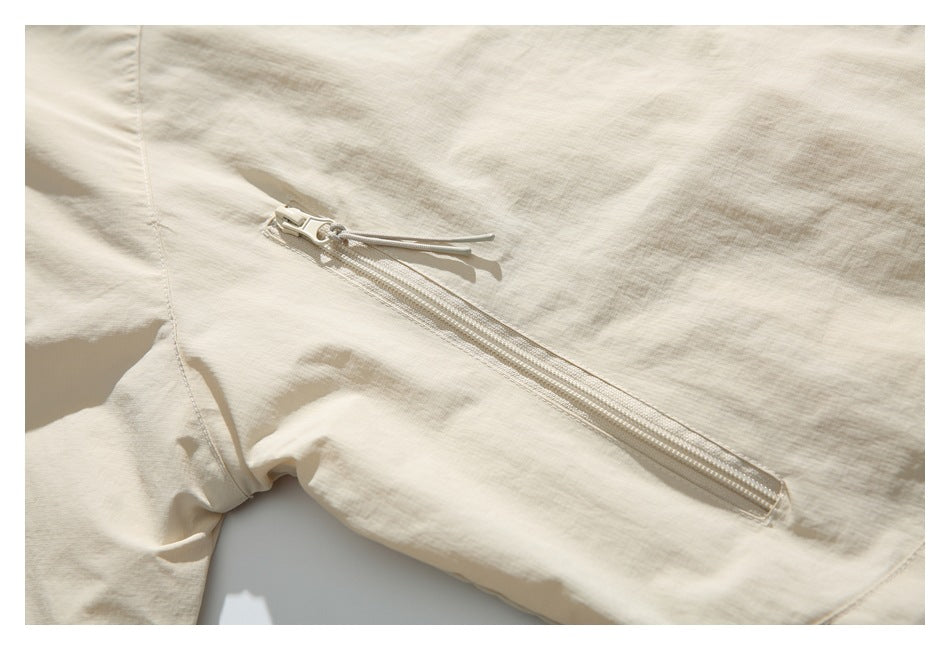 Close-up of a light beige jacket with a diagonal zipper and corded pull.