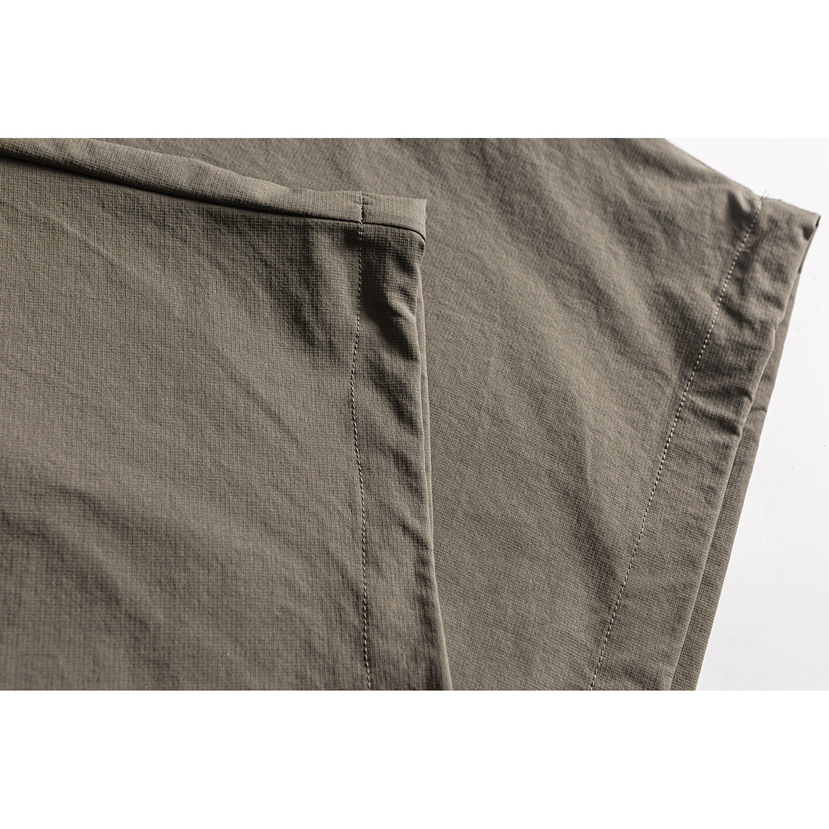Close-up of olive-gray trouser fabric and stitched seam details.