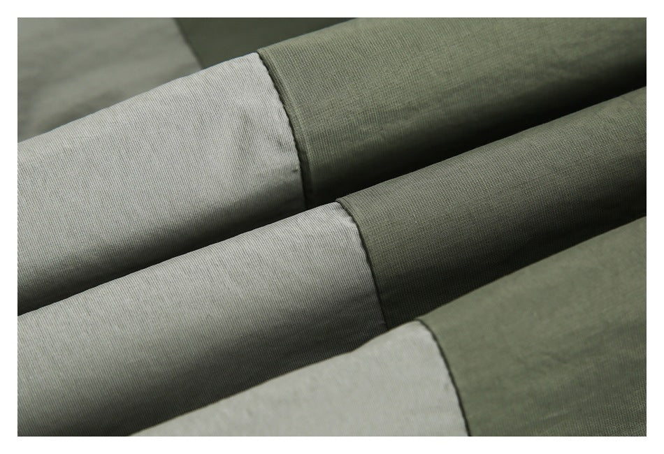 Close-up of olive-gray fabric panels folded to show their fine woven texture and seams.