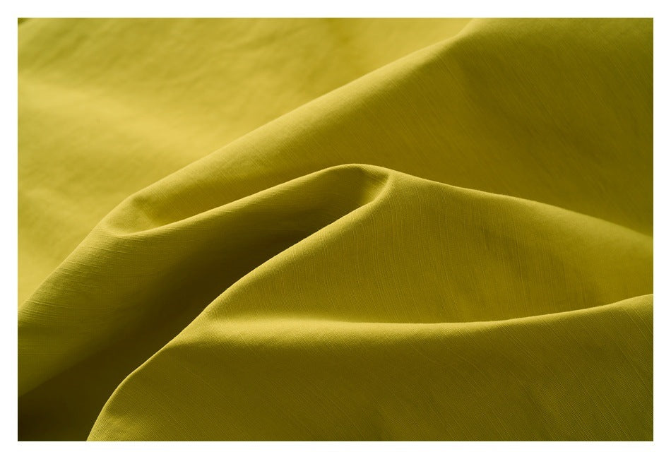 Mustard-yellow fabric shown in soft folds, highlighting its surface texture.