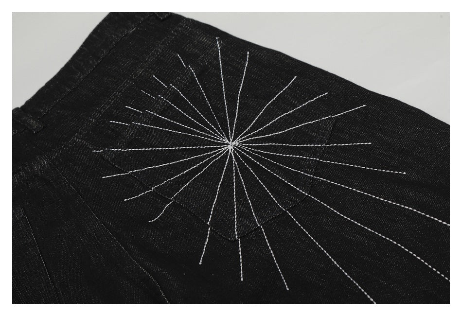 Close-up of a white radiating stitched design across black denim.