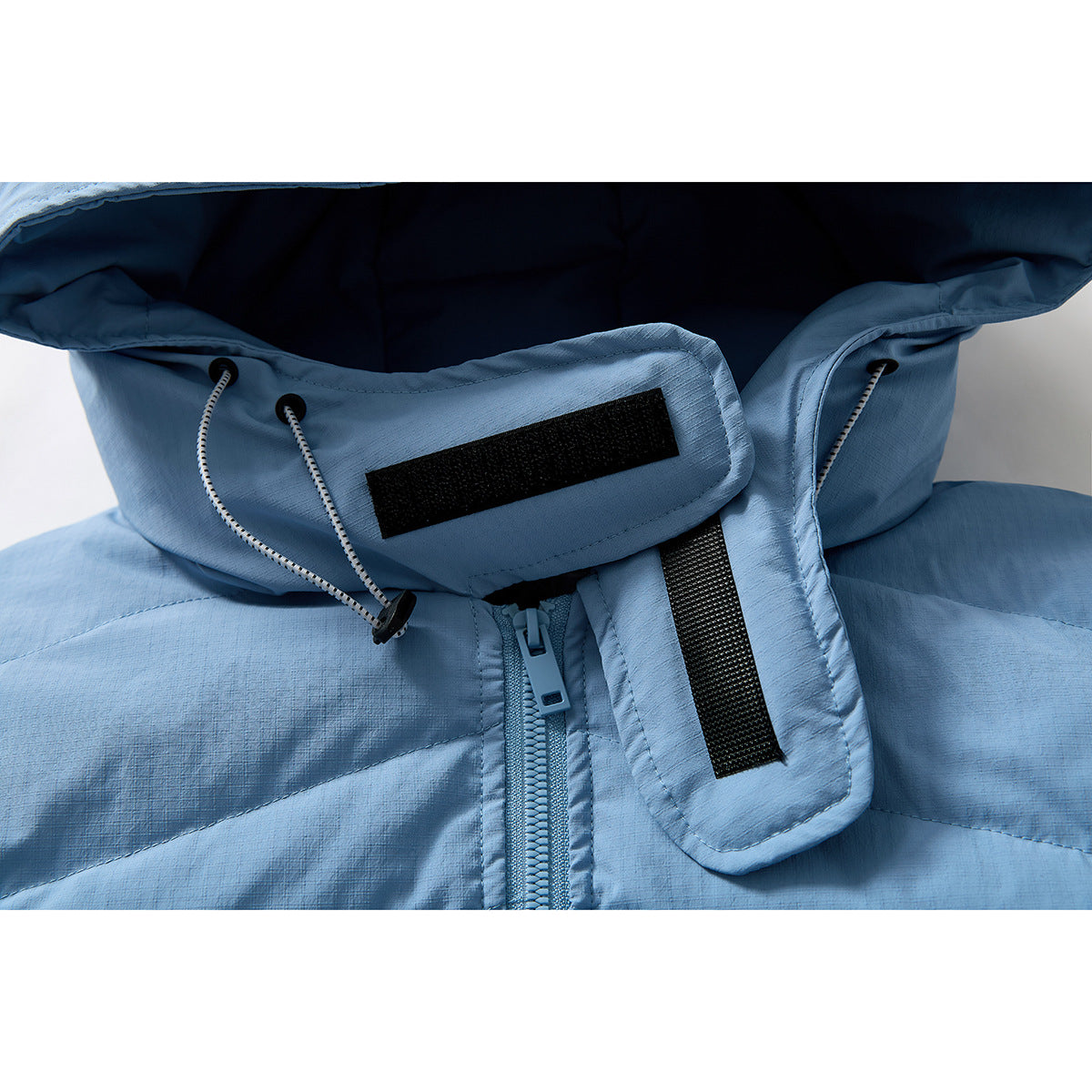 Close-up of a light blue jacket hood with drawcords, hook-and-loop tabs, and front zipper.