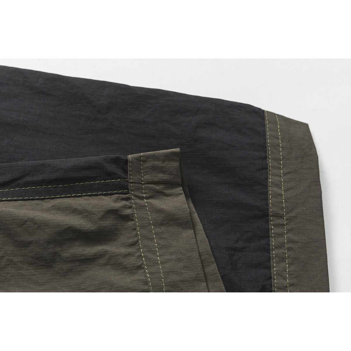 Close-up of charcoal shorts showing a contrast-panel pocket and stitched hem.