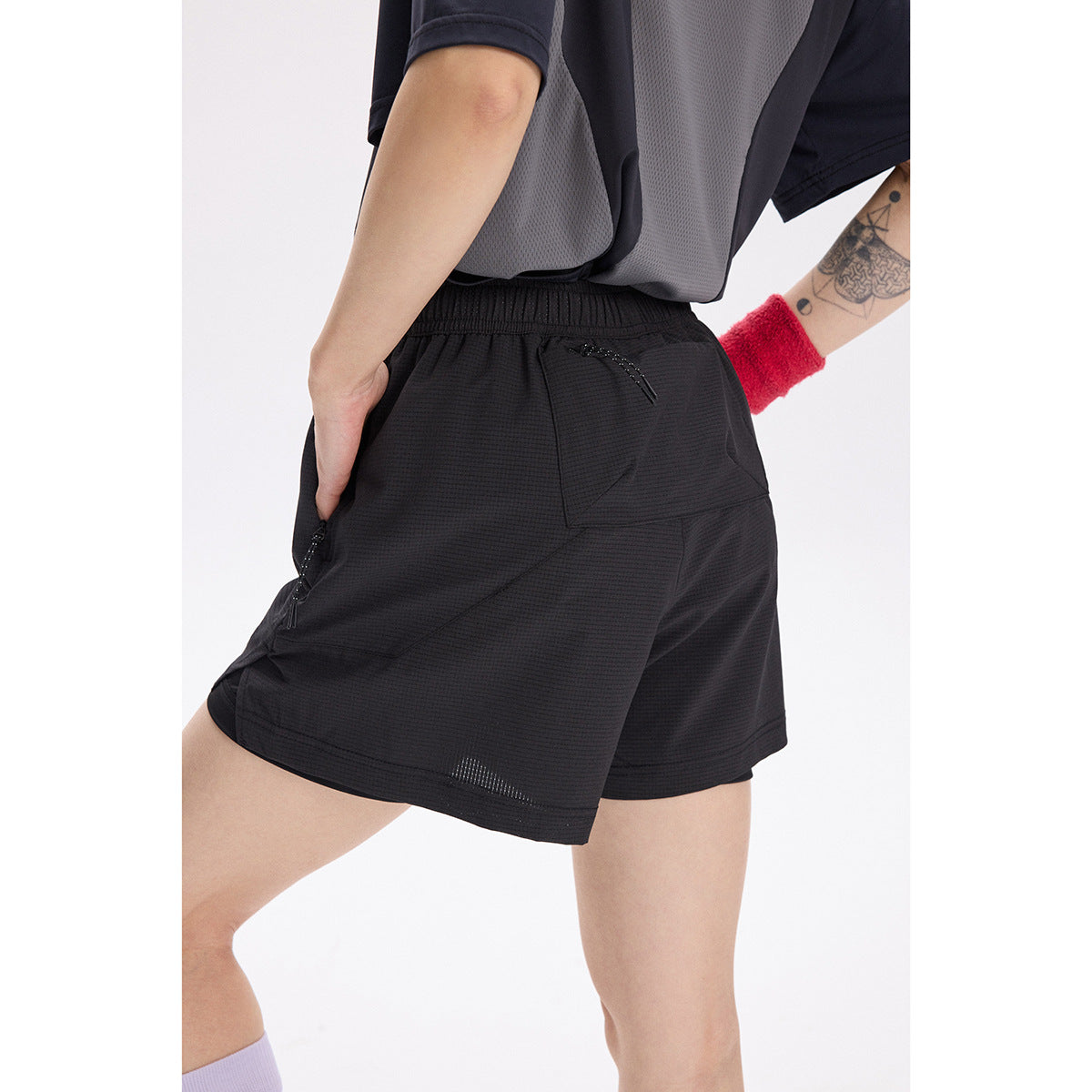 Close rear view of a model wearing black running shorts with an elastic waistband and zip pockets.