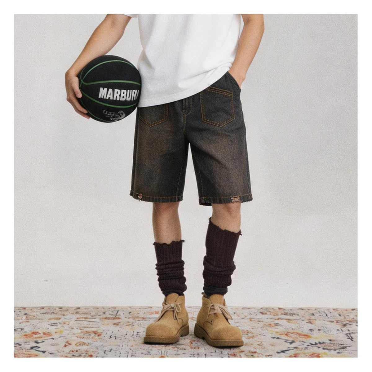 Person wearing faded dark denim shorts with white tee, dark socks and tan boots, holding a basketball, cropped at the torso