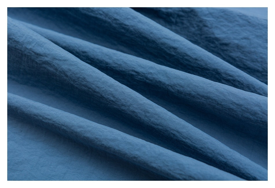 Close-up of blue garment fabric arranged in soft folds, showing its surface texture.