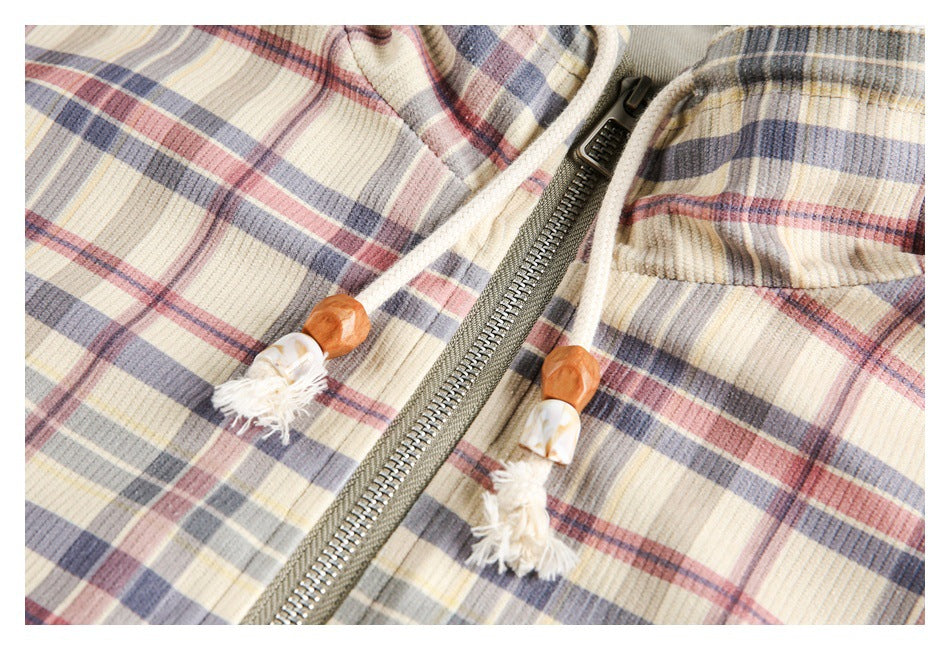 Close-up of a cream plaid jacket with a metal zipper and cream drawstrings finished with wood-tone toggles.