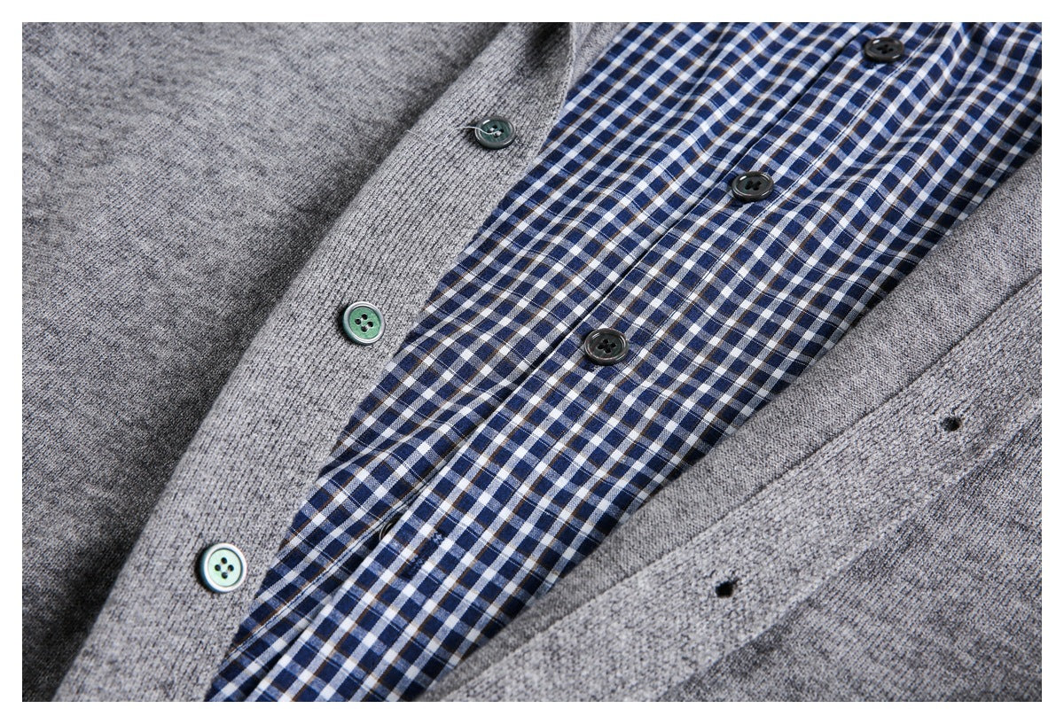 Close-up of a gray cardigan opening over a blue-and-white checked shirt, showing buttons and buttonholes.