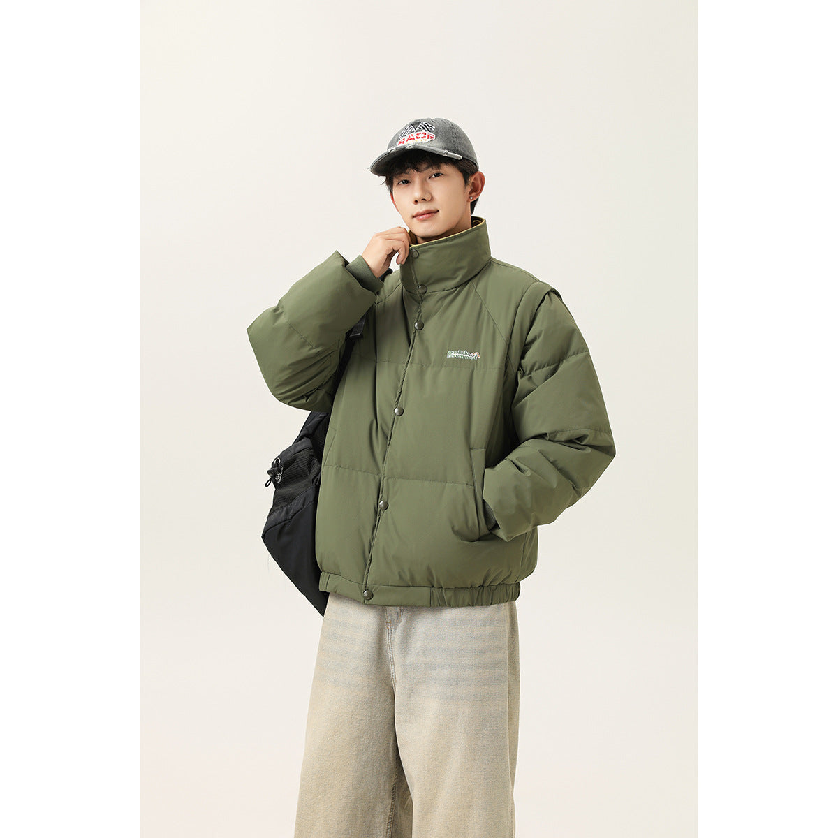 Model wearing an olive-green padded jacket with a high snap-button collar and elastic hem.