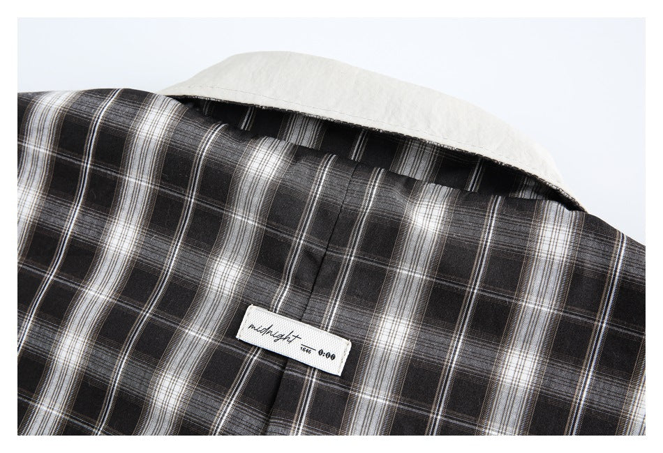 Close-up of the jacket’s back collar, center seam, and small sewn label on black-and-white plaid fabric.