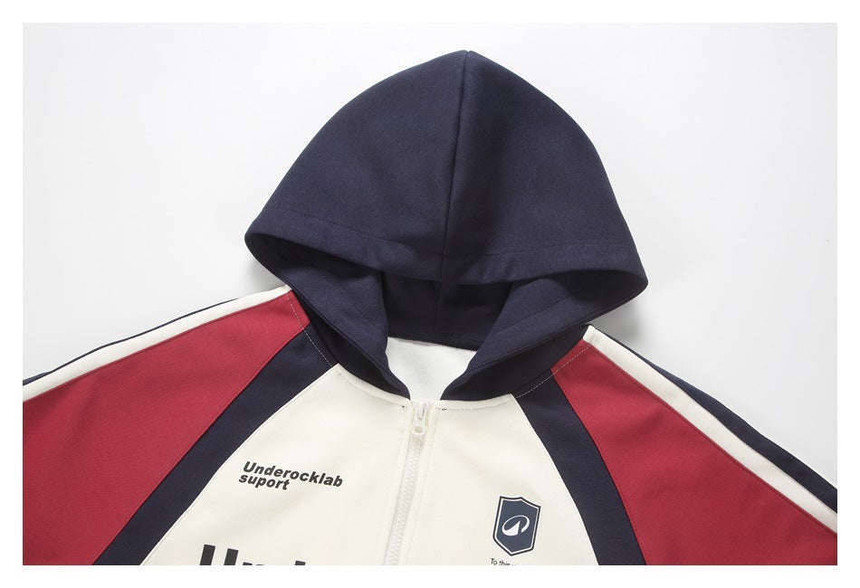 Cropped front view of a cream zip-up hoodie with a navy hood and red and navy color-block sleeves.