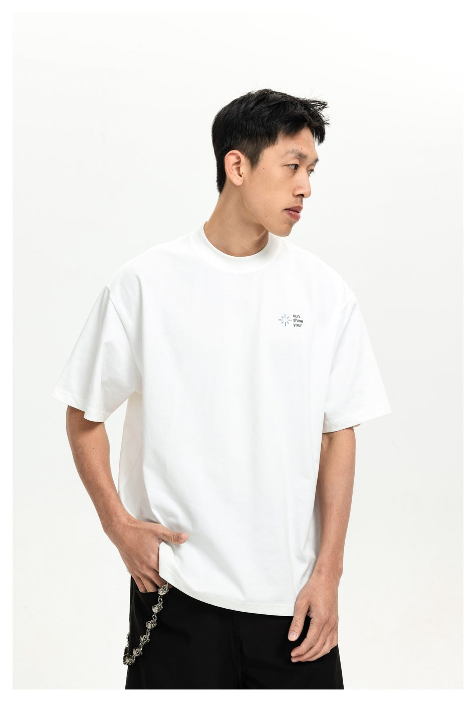 Model wearing a white oversized T-shirt with a small sun-and-text graphic on the chest.