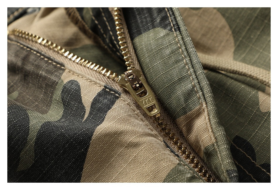 Macro view of the metal zipper and stitching on the camouflage shorts.