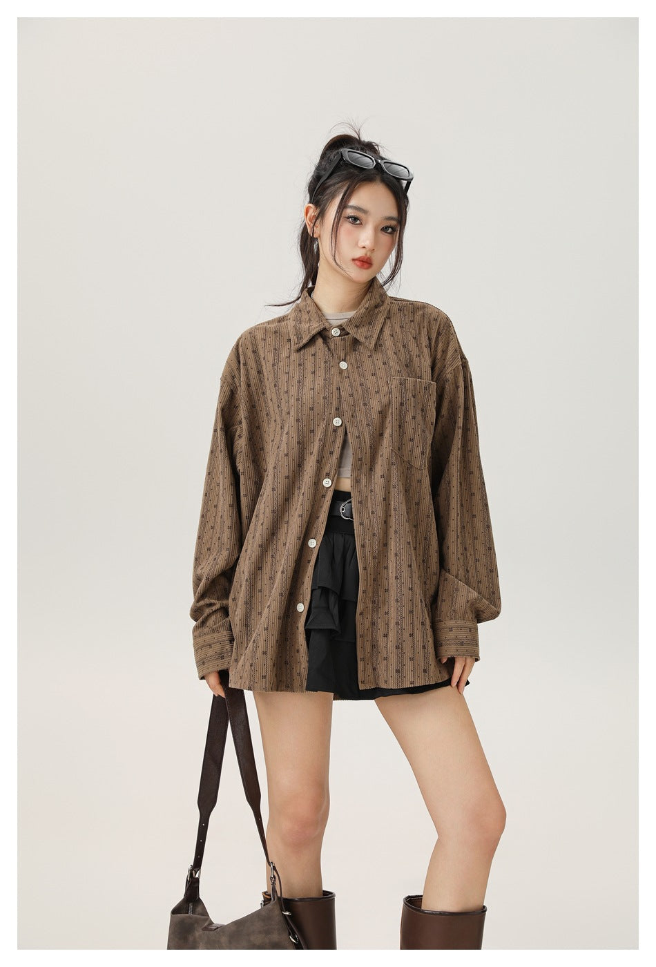 Closer front view of a model wearing an oversized brown patterned button-up shirt with a chest pocket.