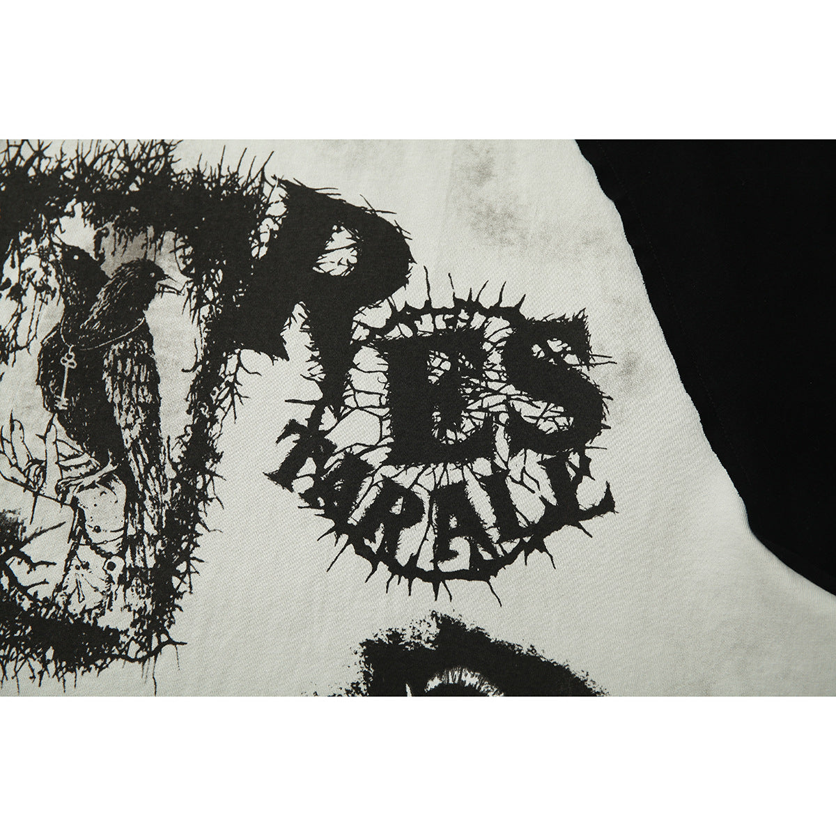 Close-up of distressed black graphic lettering printed on the light-gray body of a raglan shirt.