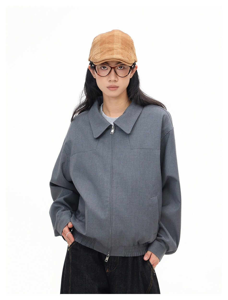 Front view of a model wearing a gray jacket with a wide collar and two-way zipper.