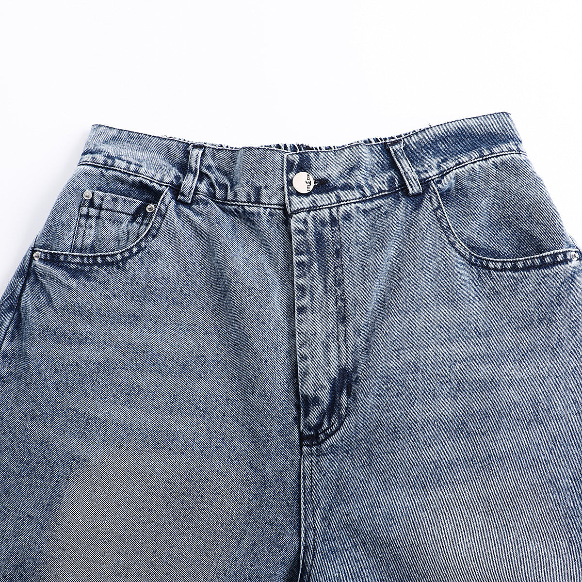 Close-up of the front waist and upper legs of blue acid-wash jeans with belt loops and curved pockets.
