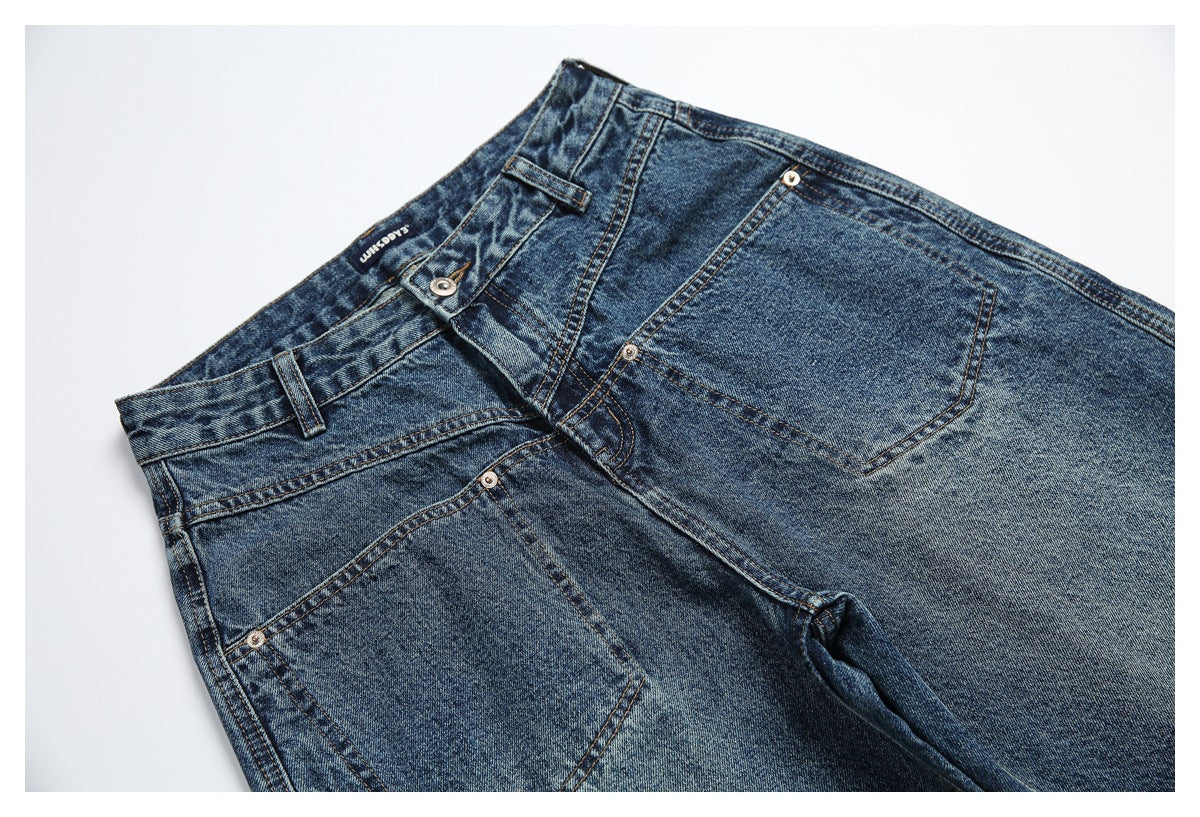Angled close-up of blue-wash jeans showing the front waistband, pockets, belt loops, and metal rivets.