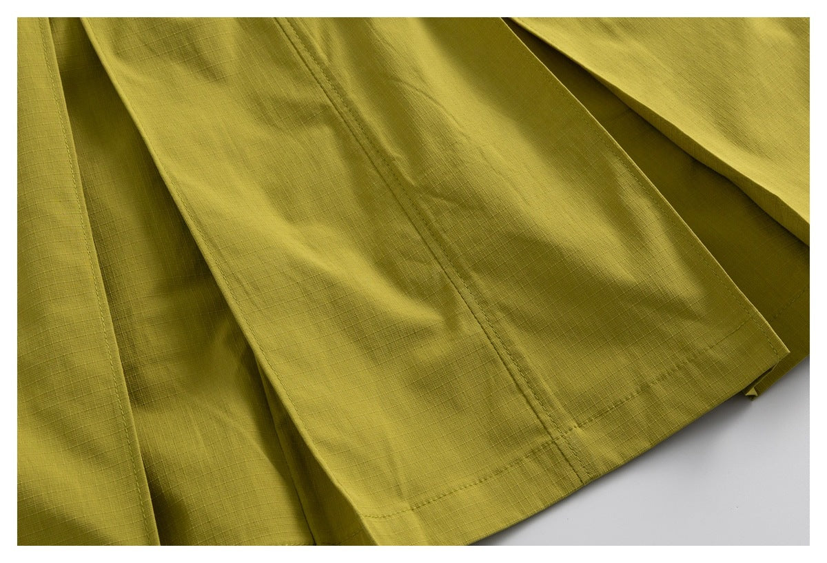 Close-up of olive-yellow shorts showing fabric panels, stitched seams and hem details.