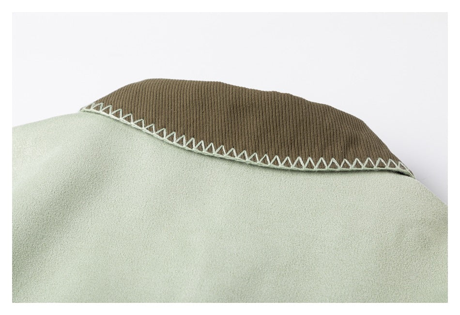Close-up of a brown ribbed collar with pale zigzag stitching on a sage-green garment.