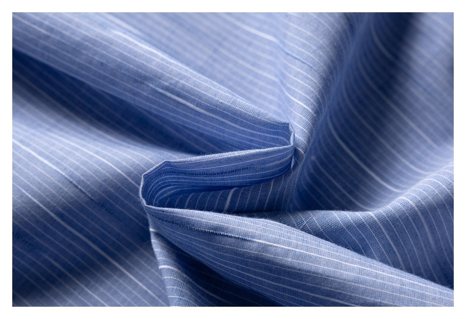 Blue fabric with fine white pinstripes shown draped to reveal its folds and edge stitching.