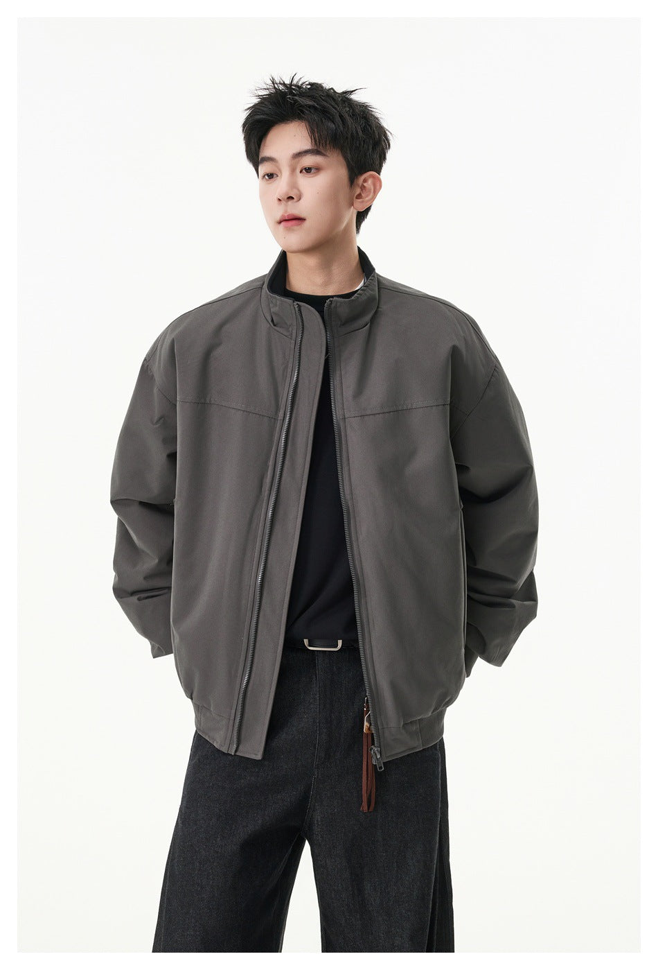 Model wearing an oversized charcoal-gray zip jacket with a stand collar over a black top.