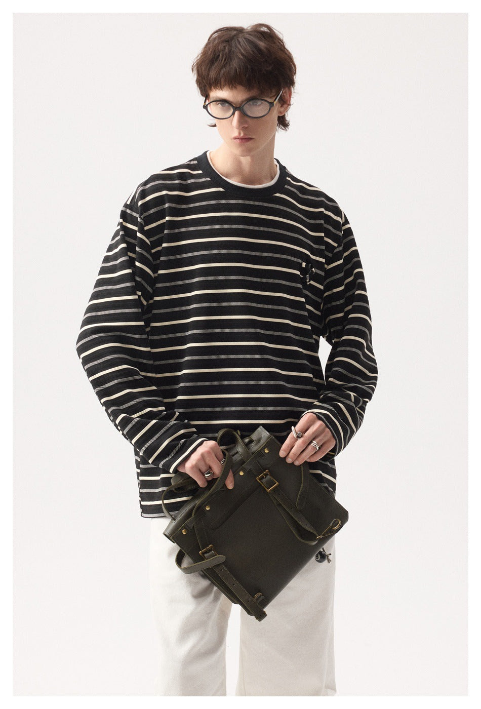 Model wearing an oversized black long-sleeve shirt with cream and gray stripes and a small chest embellishment.