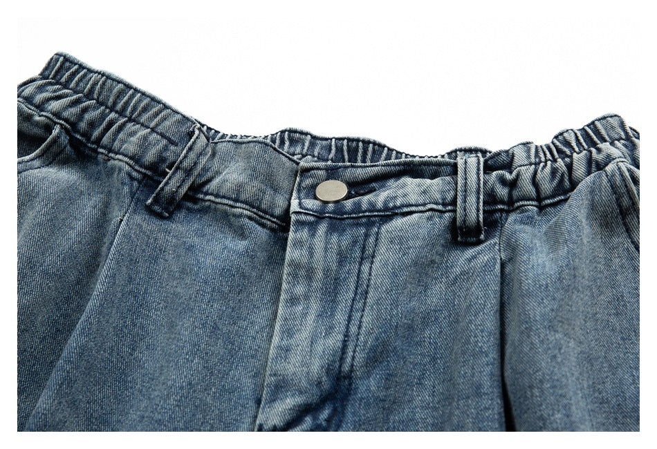 Close-up of blue denim pants with an elasticized waistband, belt loops, and a metal button.