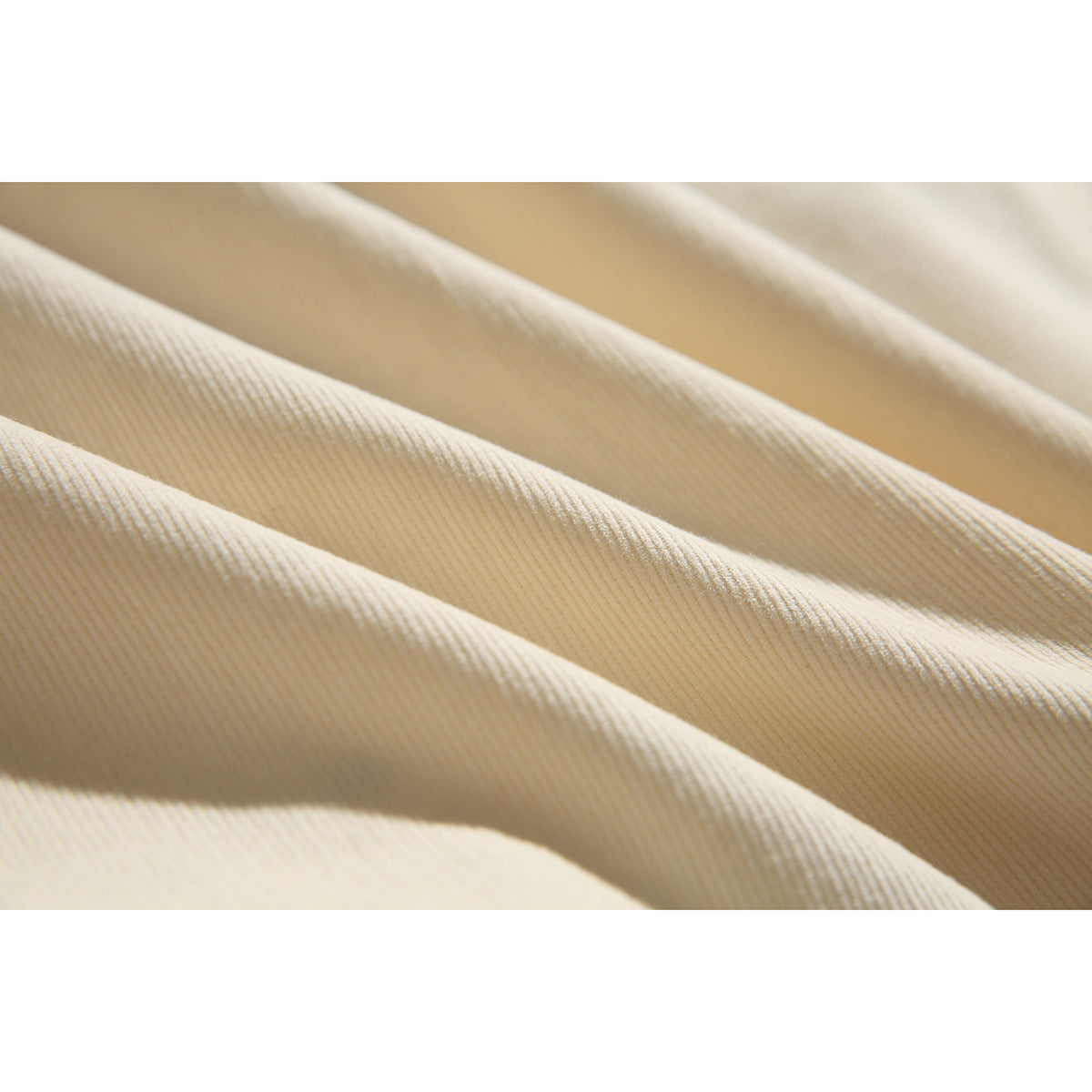 Macro view of the cream garment's ribbed fabric texture and folds.