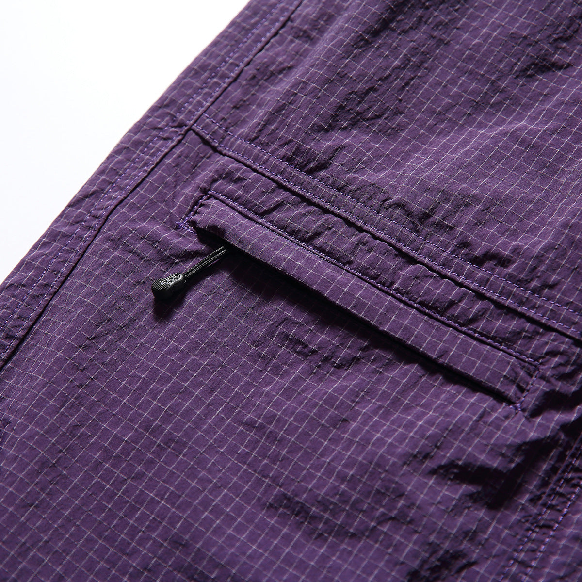 Close-up of purple windowpane-check shorts with a flap pocket and zip closure.