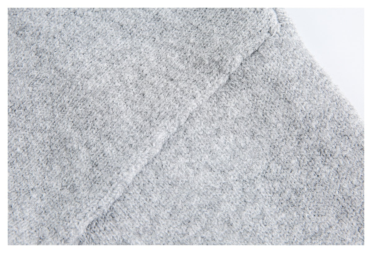 Close-up of light gray knit fabric showing a raised seam across the textured surface.