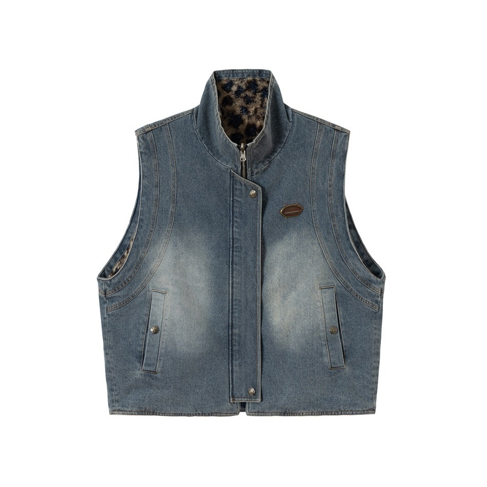 Washed blue denim stand-collar vest with front zip, snap pockets, chest badge and leopard-print pile lining at the collar