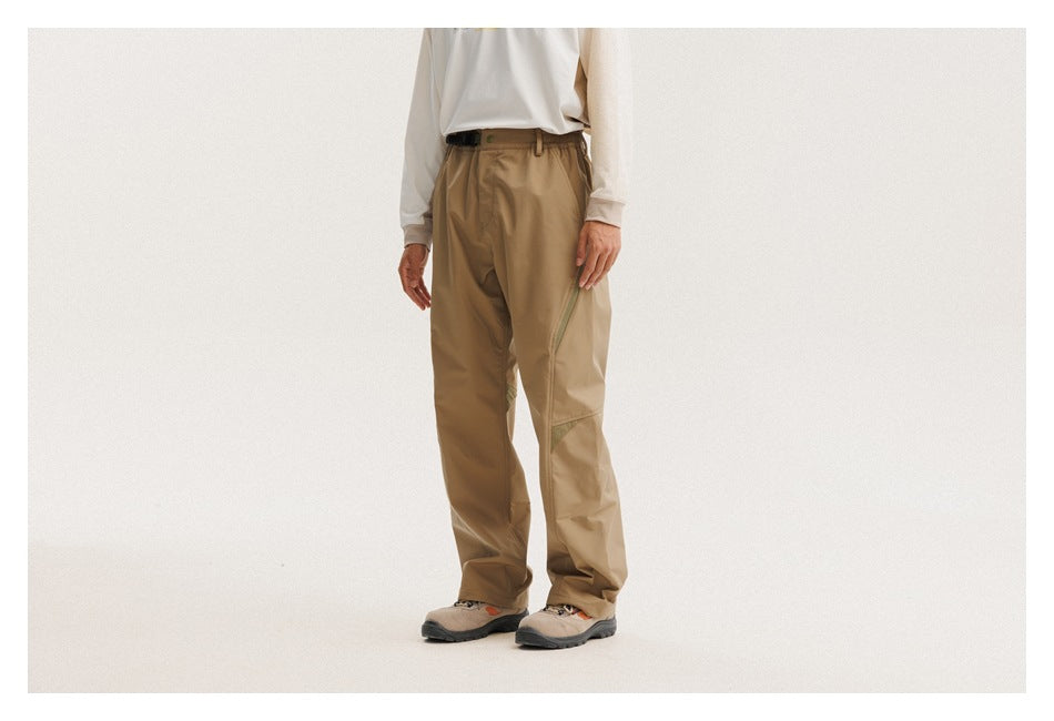 Front view of a person wearing tan outdoor pants with a black belt and hiking shoes.