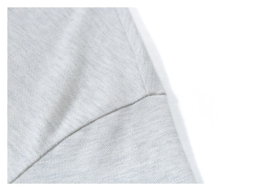 Close-up of a stitched seam on light gray shirt fabric.