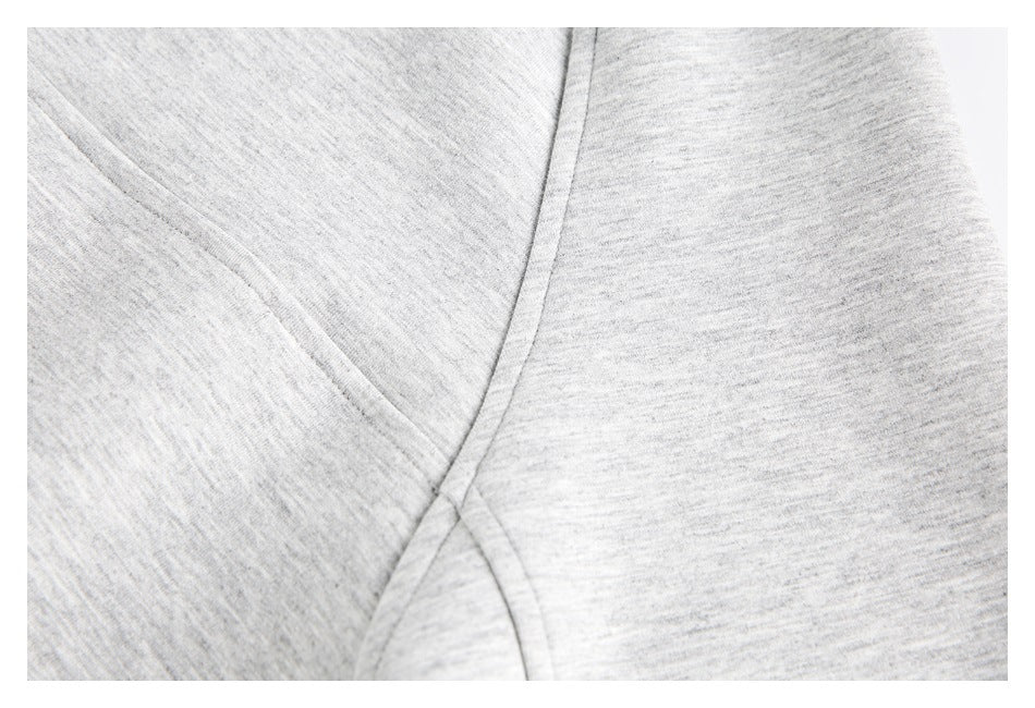 Close-up showing a curved stitched seam on light gray heathered fabric.