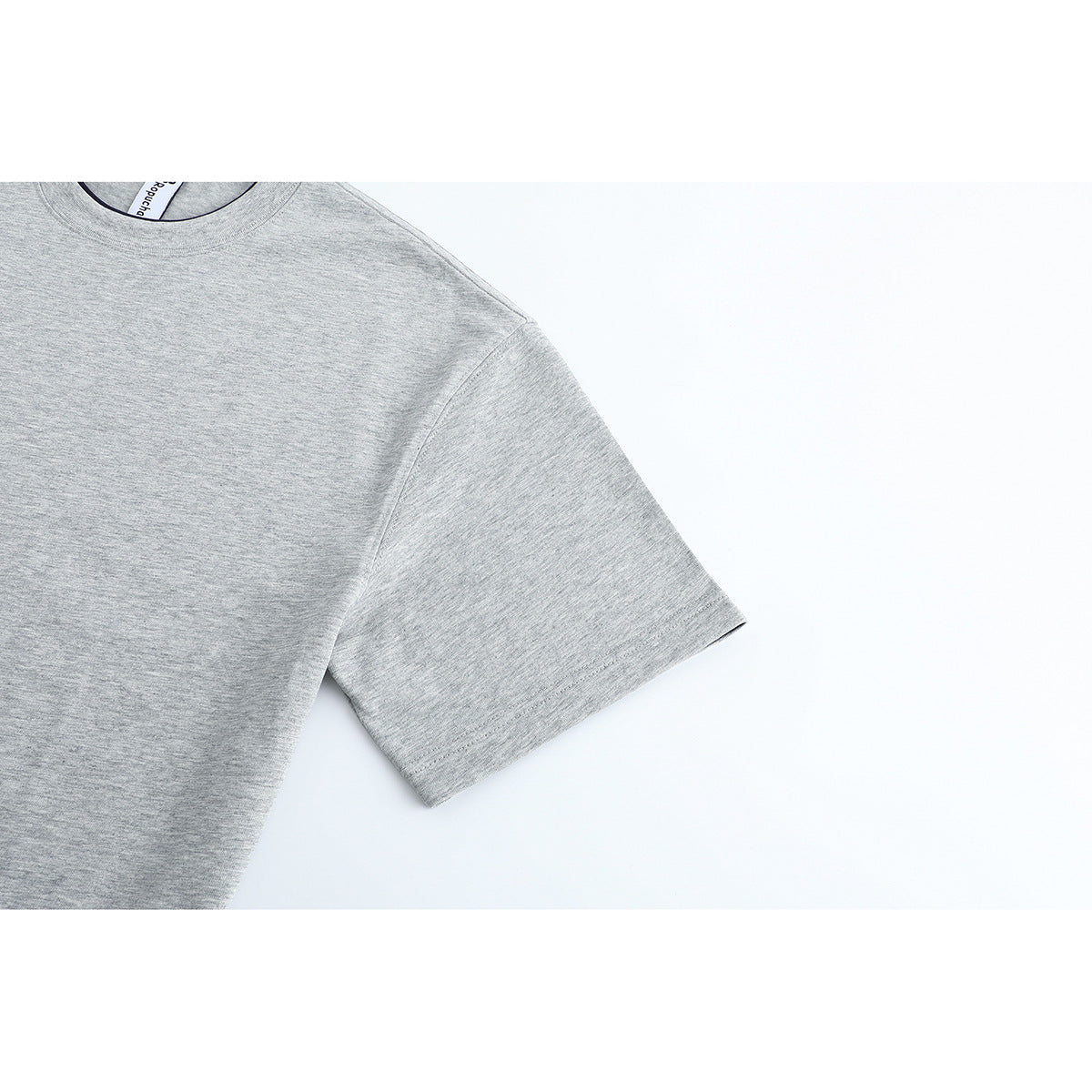 Close-up of the light gray T-shirt's short sleeve, shoulder seam, and heathered surface.
