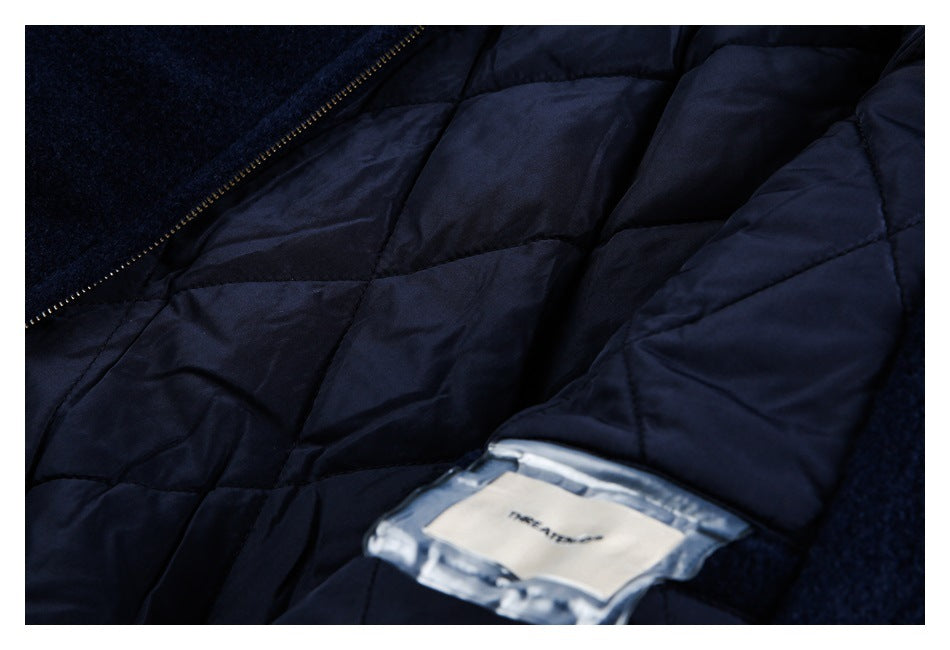 Close-up of navy quilted fabric and a zipper, with part of a clear pocket and white label visible.